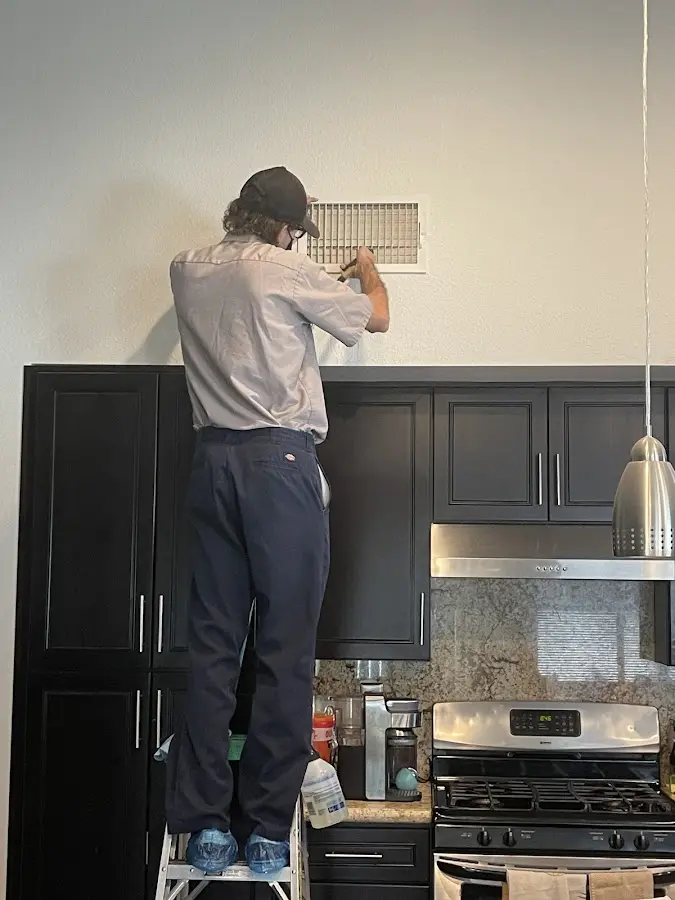 Technician inspecting an air vent during HVAC service in Claymont